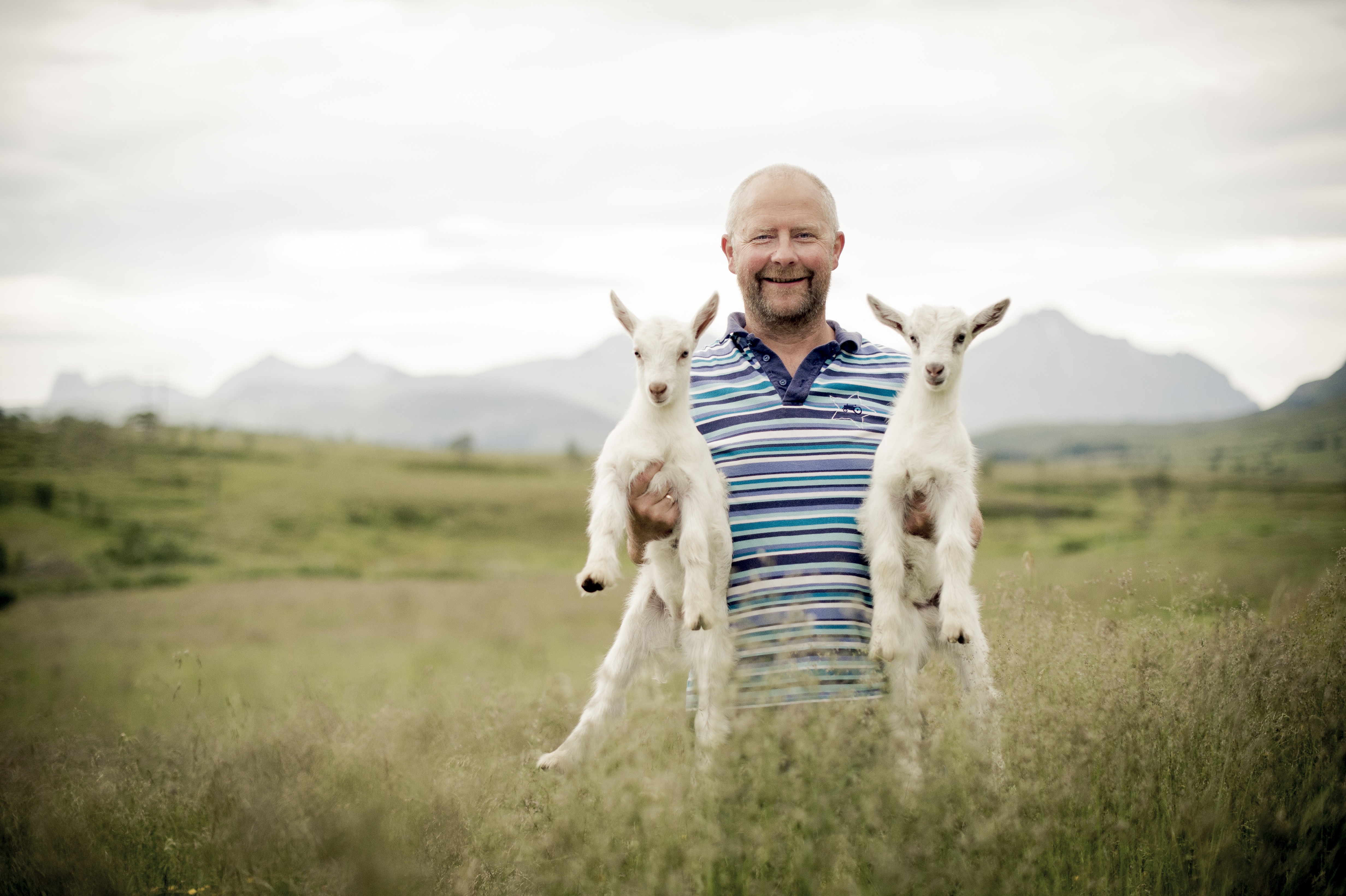 Mann som løfter to geiter