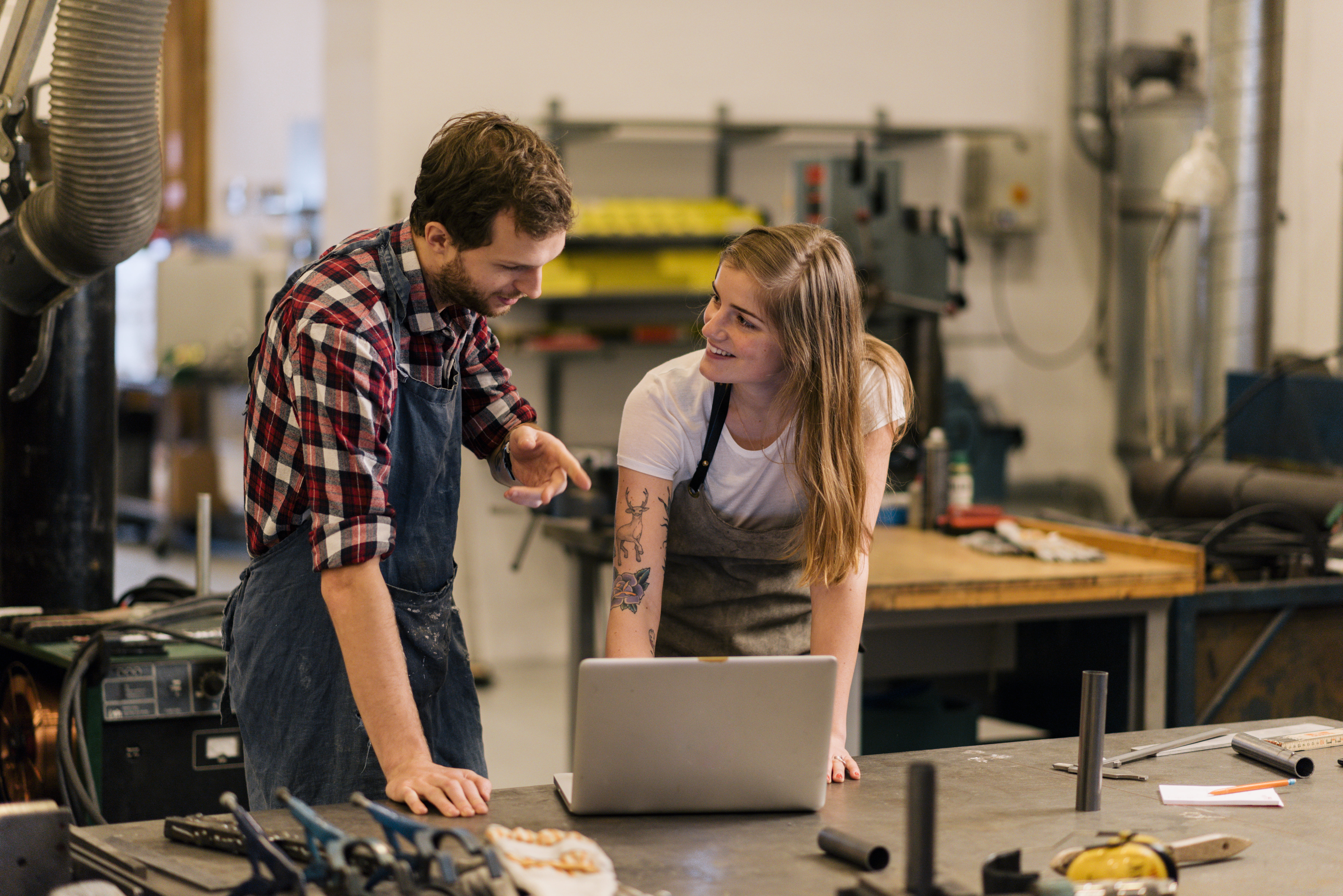 To ansatte i et verksted står og ser på en PC