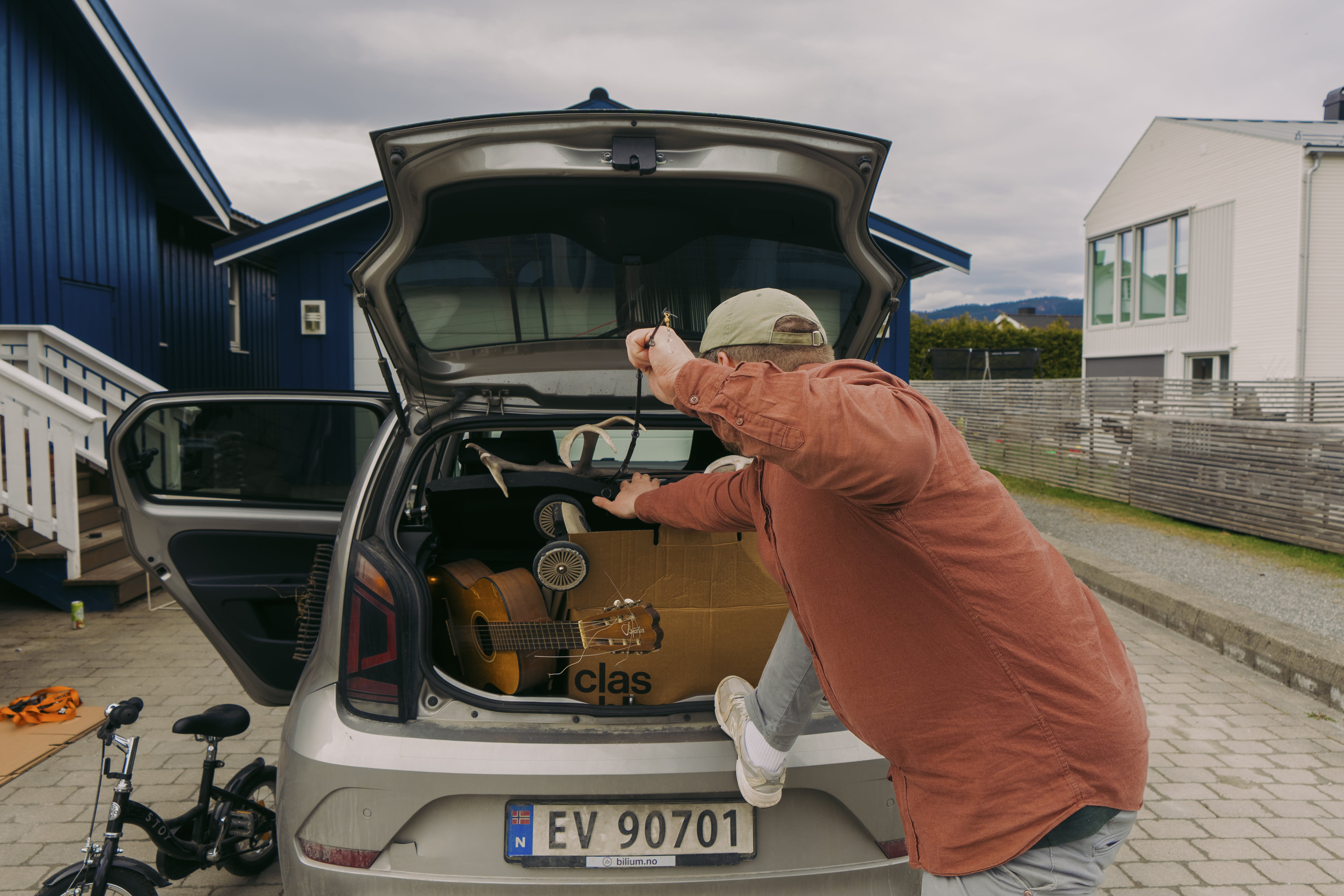 Mann stapper ting inn i en liten bil