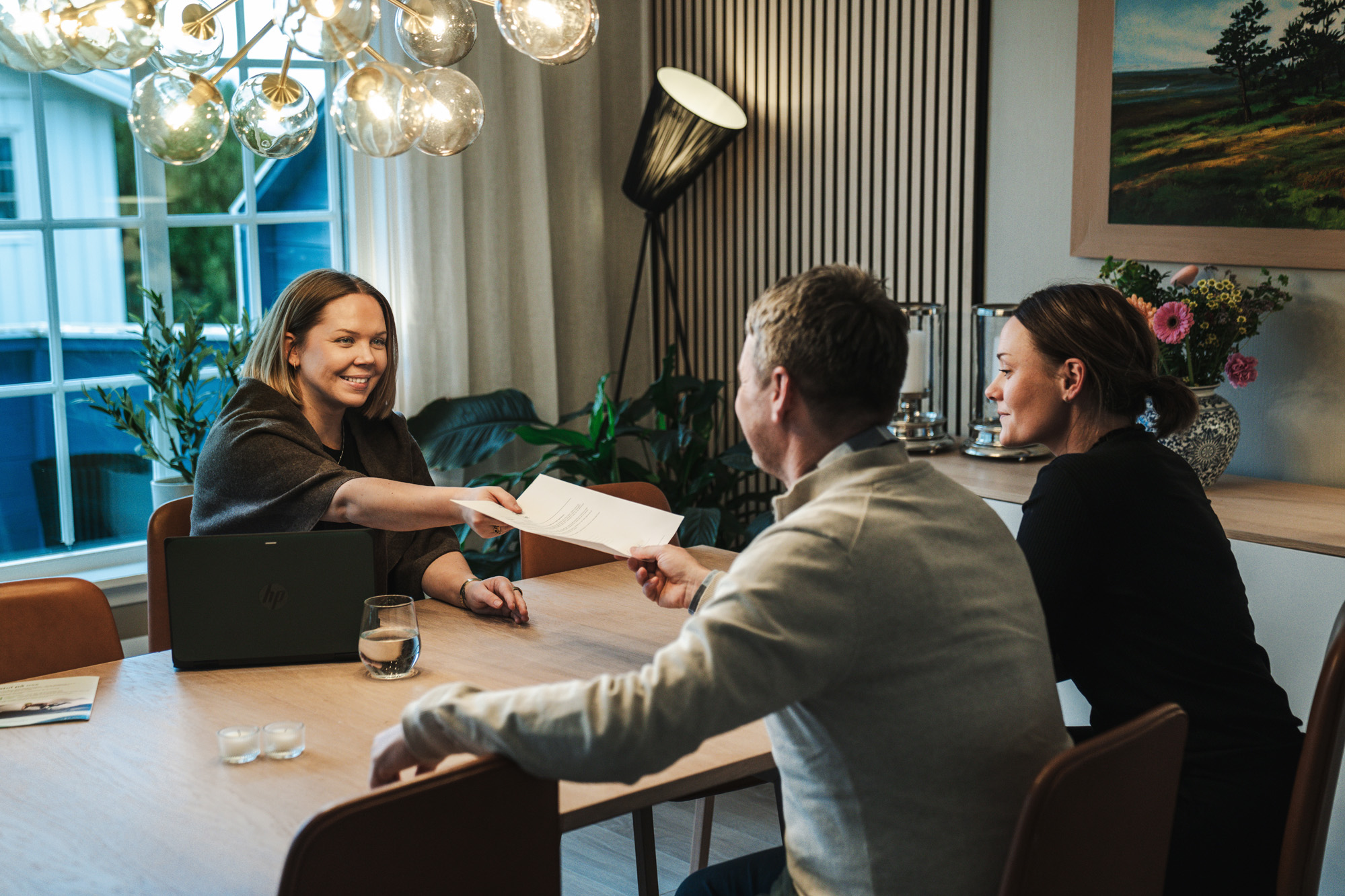 En blid kvinne gir et ungt par et dokument over bord