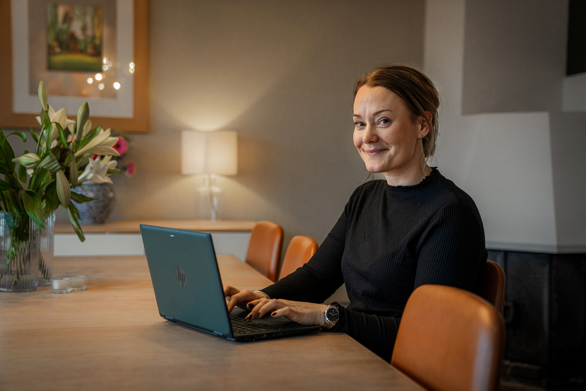 En ung kvinne sitter med laptopen på et spisebord